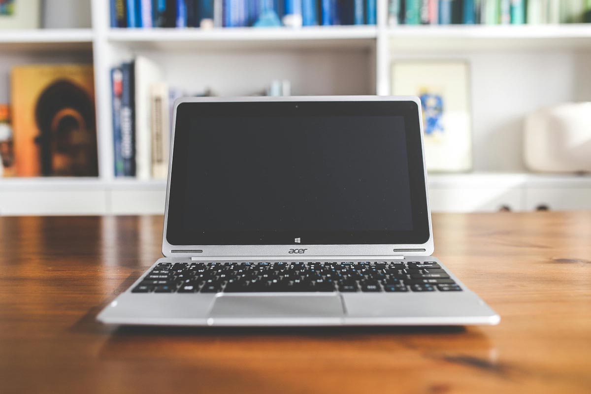 Acer laptop on a wooden desk with a blurred bookshelf in the background, representing recertified devices from top brands